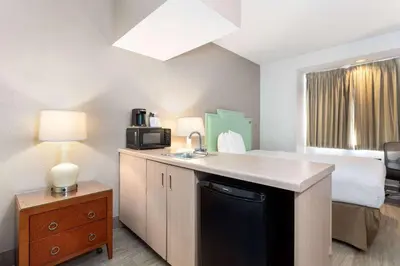 a room with a bed and a kitchen with a sink at Baymont by Wyndham Orlando-International Dr-Universal Blvd in Orlando