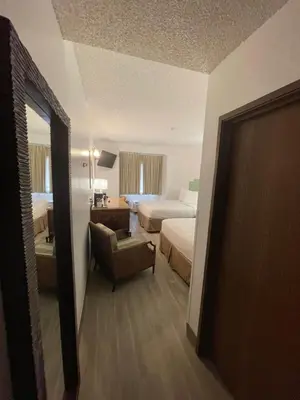 a hotel room with two beds and a chair at Baymont by Wyndham Orlando-International Dr-Universal Blvd in Orlando