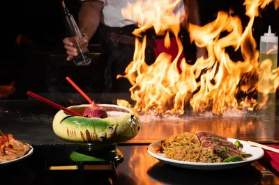 a table with plates of food in front of a fire at Mai Hana Hotel and Suites I Drive-Theme Parks in Orlando