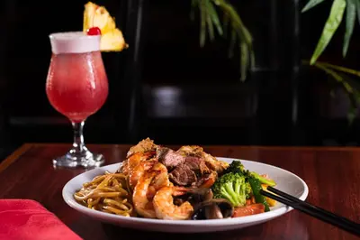 a plate of food with shrimp and broccoli and a drink at Mai Hana Hotel and Suites I Drive-Theme Parks in Orlando