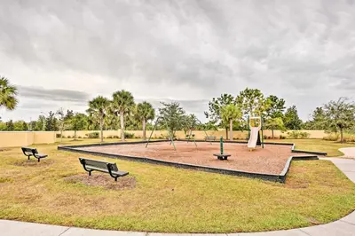 a park with benches and a fountain in the grass at Theme Park Retreat with 5-Star Amenities - By Disney in Kissimmee