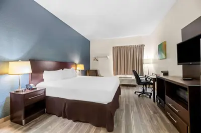 a hotel room with a large bed and a desk at Suburban Studios Orlando - Ocoee-Winter Garden in Orlando