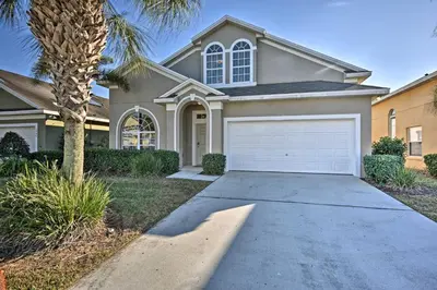a house with a garage and a palm tree at 10 Mi to Disney Resort Home with Pool and Spa in Orlando