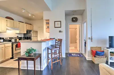 a kitchen and living room with a counter and chairs at Resort-Style Condo with Pool 6 Mi to Magic Kingdom in Kissimmee