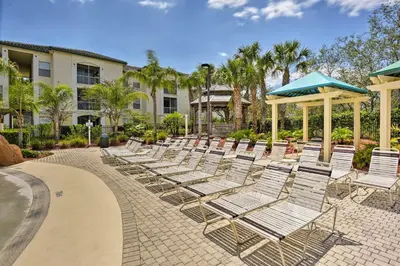 a row of lounge chairs on a patio at Resort-Style Condo with Pool 6 Mi to Magic Kingdom in Kissimmee