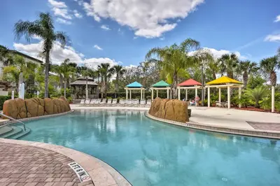 a swimming pool at a resort with palm trees at Resort-Style Condo with Pool 6 Mi to Magic Kingdom in Kissimmee