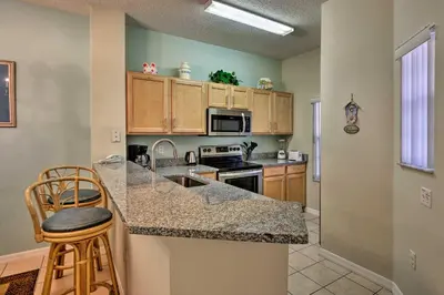 a kitchen with wooden cabinets and a counter top at 5 Mi to Disney Emerald Island Resort Condo! in Kissimmee
