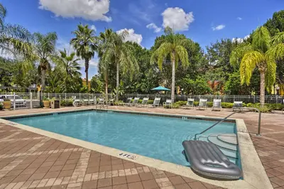 a swimming pool with a chair and palm trees at 5 Mi to Disney Emerald Island Resort Condo! in Kissimmee