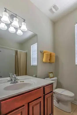 a bathroom with a sink and a toilet and a mirror at Spacious Kissimmee Villa - 3 Mi to Disney World! in Orlando