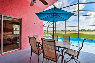 a dining room with a table and a blue umbrella at 5 Mi to Disney Parks Kissimmee Home with Game Room in Kissimmee