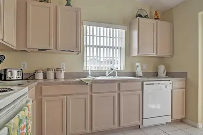 a kitchen with white cabinets and a sink and a window at Beautiful Kissimmee Home - 5 Mi to Disney World! in Kissimmee