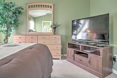 a bedroom with a flat screen tv on a wooden dresser at Beautiful Kissimmee Home - 5 Mi to Disney World! in Kissimmee