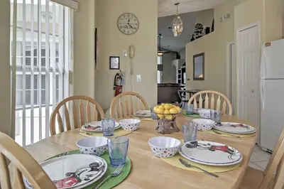a dining room table with plates and bowls of fruit on it at Beautiful Kissimmee Home - 5 Mi to Disney World! in Kissimmee