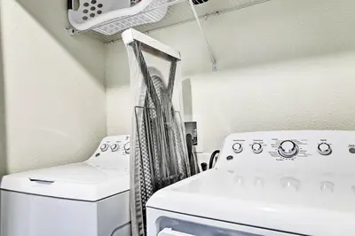 a laundry room with a washing machine and a chair at about 6 Mi to Disney Kissimmee Retreat with Pool! in Kissimmee