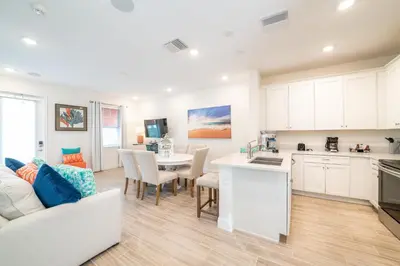 a kitchen and living room with a couch and a table at Sunset Sands Cottage Near Disney With Margaritaville Resort & Island H2O Access - 8065Dr in Orlando