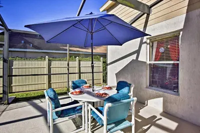 a table with chairs and an umbrella on a patio at 12 Mi to Disney Home with Pool and Spa in Clermont in Orlando