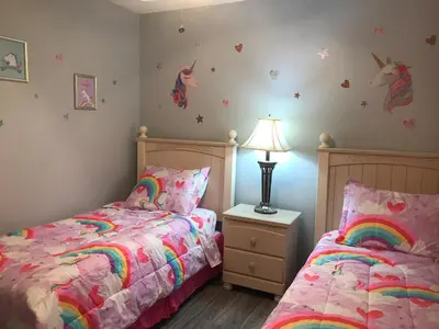 a bedroom with two beds and a unicorn on the wall at 7 Bedroom, 6 bath and pool near Disney in Emerald Island 4 King Master Suites in Kissimmee