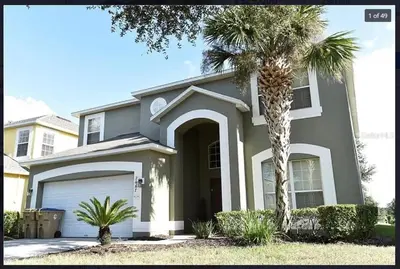a house with a palm tree in front of it at 7 Bedroom, 6 bath and pool near Disney in Emerald Island 4 King Master Suites in Kissimmee