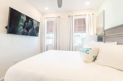 a white bedroom with a large white bed and a tv at Blue Cascade Cottage Near Disney With Margaritaville Resort & Island H2O Access - 8064Ls in Orlando