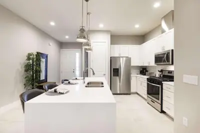 a large white kitchen with a large white counter top at Cozy Villa 5 Min to Disney w BBQ, SMV104 in Orlando