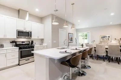a kitchen with white cabinets and a large island with bar stools at Cozy Villa 5 Min to Disney w BBQ, SMV104 in Orlando