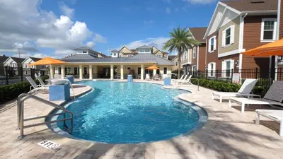 a swimming pool with chairs and a house at Ultra convenient stay, 5 min to Disney SMV118 in Orlando