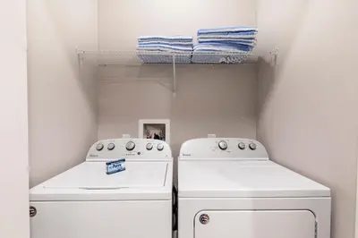 two whitewashes in a laundry room with towels on a shelf at Comfy Villa 5 Min to Dinsey! Hot Tub & BBQ in Orlando