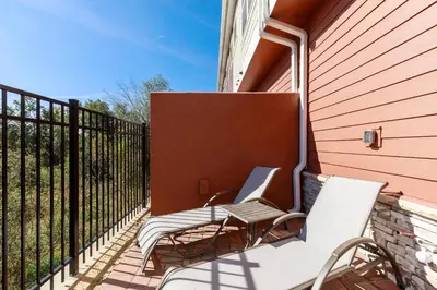 a balcony with two chairs and a fence at Fantastic Townhome 5min Disneyworld 134 in Orlando