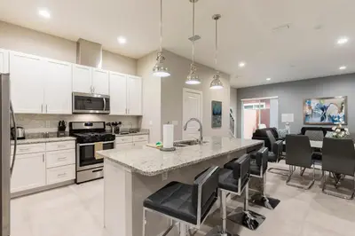 a kitchen with white cabinets and a large island with bar stools at Amazing Hidden Gem, Min Disney 139 in Orlando