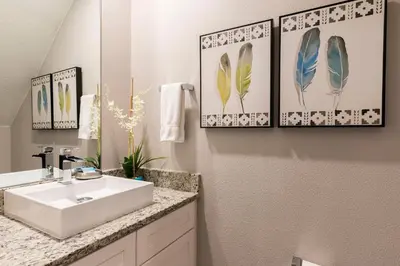 a bathroom with a sink and two framed pictures of feathers at Amazing Hidden Gem, Min Disney 139 in Orlando