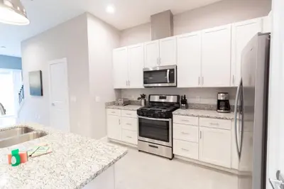 a kitchen with white cabinets and a stove top oven at Amazing Family Villa, 5min Disney SMV144 in Orlando