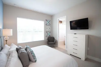 a bedroom with a white bed and a television at Amazing Family Villa, 5min Disney SMV144 in Orlando
