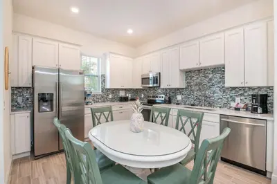 a kitchen with a table and chairs and a refrigerator at Sea Breeze Cottage Near Disney With Margaritaville Resort & Island H20 Waterpark Access - 2982La in Orlando