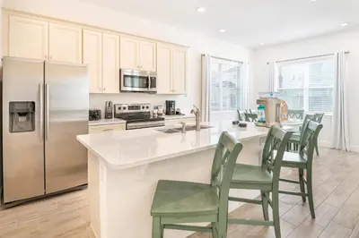 a kitchen with stainless steel appliances and green chairs at Coral Reef Cottage! Near Disney With Margaritaville Resort & Island H2O Access - 8052Ls in Orlando