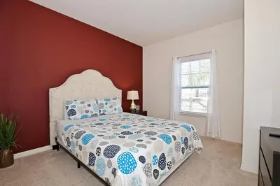 a bedroom with a bed and a red wall at Great townhouse in gated community West Lucaya in Kissimmee
