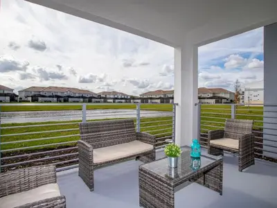 a porch with two chairs and a table with a view of a field at Marvelous 2 Bd Apt Close to Disney at Storey Lake 106 in Kissimmee