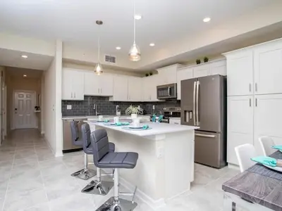 a kitchen with white cabinets and a large island with chairs at Marvelous 2 Bd Apt Close to Disney at Storey Lake 106 in Kissimmee