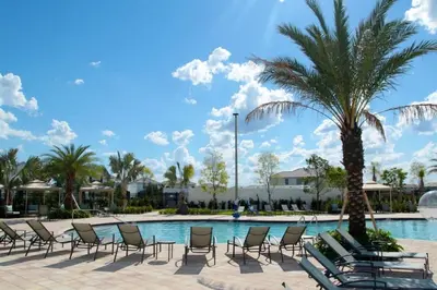 a group of chairs and a palm tree next to a pool at Marvelous 2 Bd Apt Close to Disney at Storey Lake 106 in Kissimmee