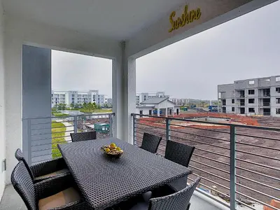 a table and chairs on a balcony with a view at Fabulous Thematic 2BR Condo with Kids Splash Pad in Kissimmee
