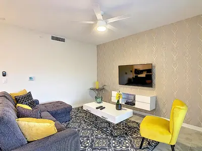 a living room with a couch and a tv at Fabulous Thematic 2BR Condo with Kids Splash Pad in Kissimmee
