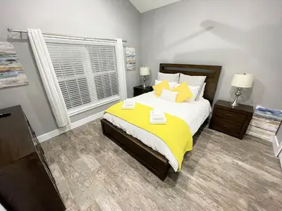 a bedroom with a bed with yellow sheets and a window at Mickeys Circle - Gorgeous! Modern 6BR, with Private South Facing Pool Hot Tub BBQ Theater 2 Miles to Disney in Orlando