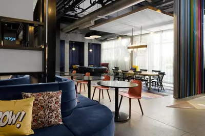 a living room with a couch and tables and chairs at Aloft Orlando Lake Buena Vista in Orlando