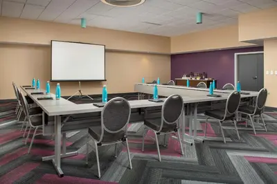 a conference room with a table and chairs and a white screen at Tru By Hilton Orlando Convention Center in Orlando