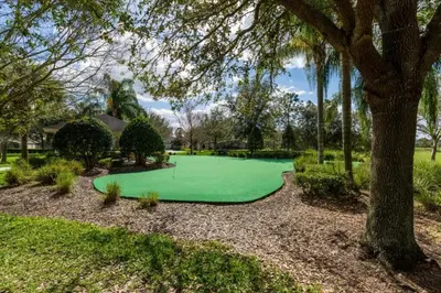 a green golf course in a park with a tree at Beautiful Condo - Windsor Hills - 2 Miles Disney in Orlando