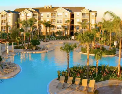 a resort with a large swimming pool with chairs and palm trees at Beautiful Condo - Windsor Hills - 2 Miles Disney in Orlando