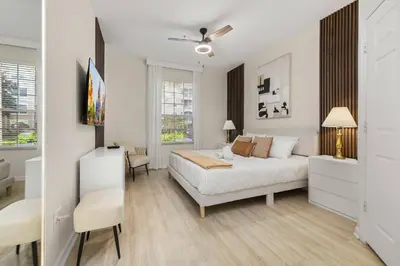 a white bedroom with a bed and a desk at Ground Floor at Windsor Hills – 5 Min Disney in Orlando