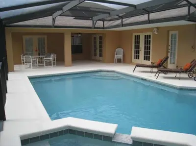 a large swimming pool with a patio with a table and chairs at Family Vacation Home With Pool and Spa Near Disney and Universal in Orlando