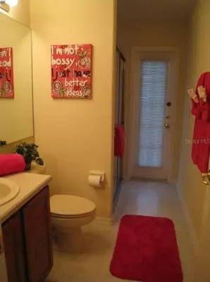 a bathroom with a toilet and a red rug at Family Vacation Home With Pool and Spa Near Disney and Universal in Orlando