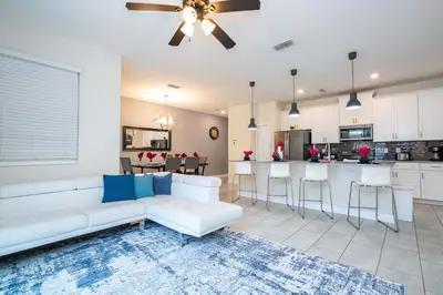 a living room with a white couch and a kitchen at Gorgeous Four Bd w/ Pool close to Disney 5035 in Kissimmee