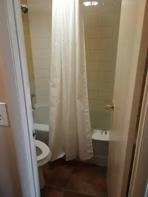 a bathroom with a white shower curtain and a toilet at Altamonte Springs Hotel and Suites in Orlando